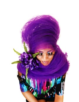 A young woman standing for white background with purple twill around her and long eye lashes, looking down.