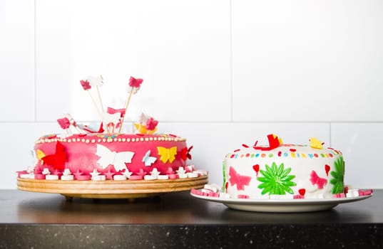 Colorful decorated white and pink Marzipan cakes for a birthday party on kitchen dresser