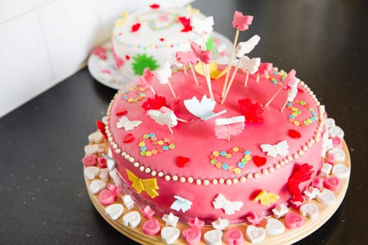 Colorful decorated white and pink Marzipan cakes for a birthday party on kitchen dresser