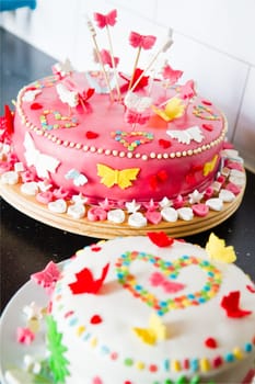 Colorful decorated white and pink Marzipan cakes for a birthday party on kitchen dresser