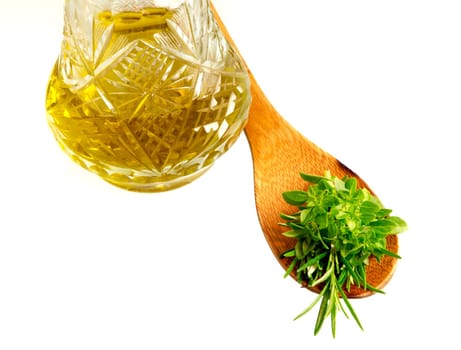 Mixed herbs in a wooden spoon next to a bottle of olive oil.