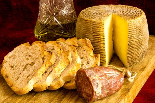 Cheese,sausage, walnuts bread andolive oil on cutting wood board.