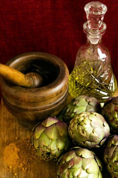 Wood cutting board with artichokes,curry,black pepper and olive oil on dark red background.