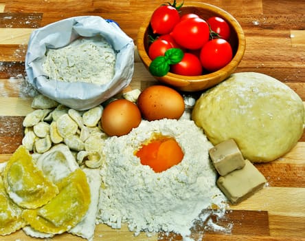 Cutting board with ingredients for the preparation of pasta or pizza.