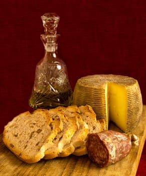 Cheese,sausage, walnuts bread andolive oil on cutting wood board.
