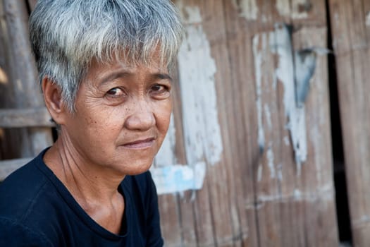 Asian senior from an impoverished area, outside her home in the Philippines