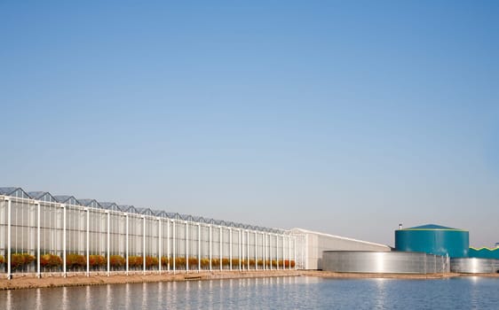 Roof of a greenhouse and water tank under a clear blue sky