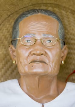 Wood carved effigy, called tau tau placed in a tongkonan looking over the land