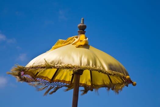 Balinese ceremonial pajeng (umbrella) against a blue sky