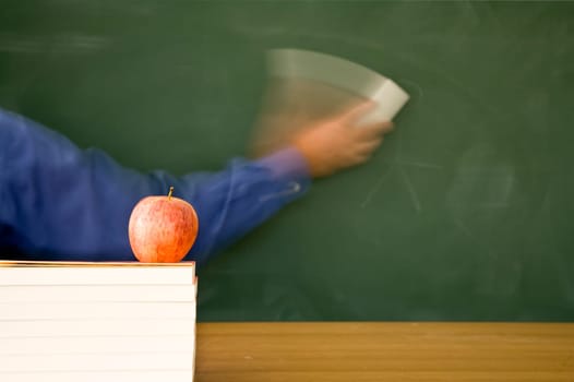 Teacher is cleaning a used green chalkboard