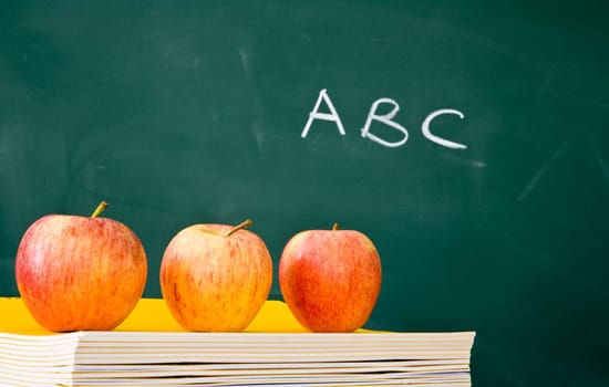 Three apples in a row with used green chalkboard in the background