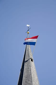 Dutch flag waving in the wind from a church tower