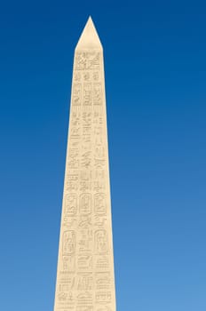 Egyptian obelisk with hieroglyphs and blue sky
