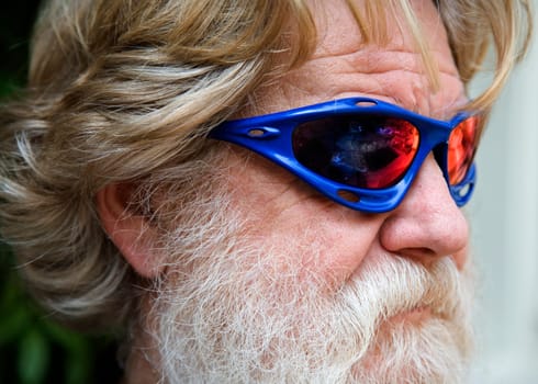 Old man with a grey beard with blue sun glasses