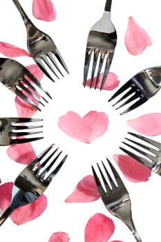 forks surrounding a heart shape petal with rose petals for a concept on romantic dining on white background with clipping path