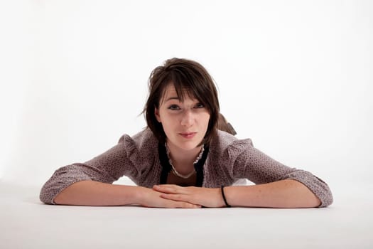 young brunette woman lenthened on the ground isolated in studio looking ahead