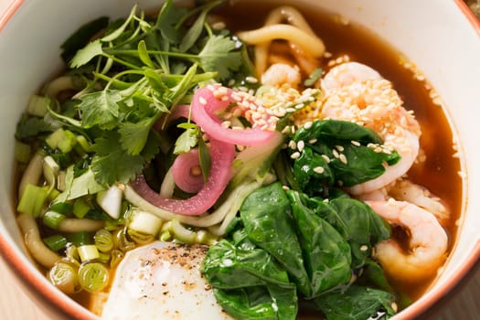 Zoomed bowl with broth and boiled shrimp between sticks