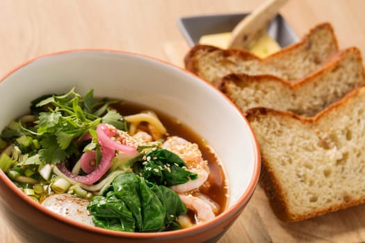 Zoomed bowl with broth and shrimp between sticks