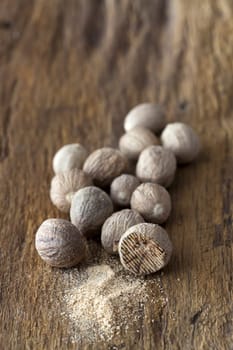 Nutmeg and powder on a rustic wooden plate