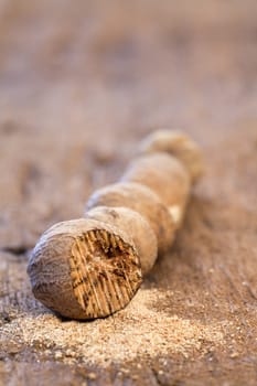 Five nutmegs in a row on a rustic wooden surface