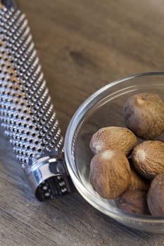 Some whole nutmegs in a glass bowl next to a musca drive