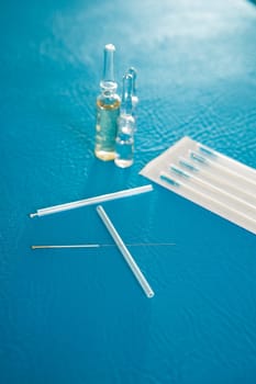 Acupuncture needles set and blister on blue leather background