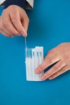 Acupuncture needles in doctor hands holding blister on blue