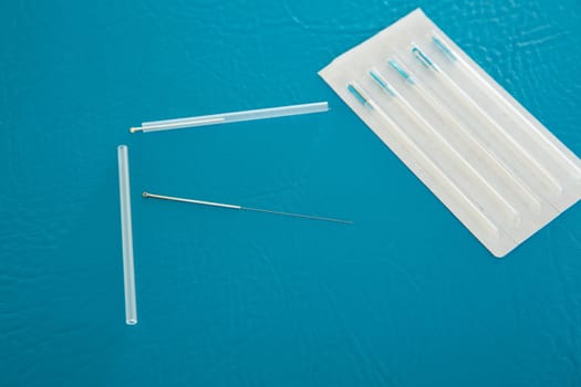 Acupuncture needles set and blister on blue leather background