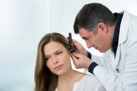 Doctor ENT checking ear with otoscope to woman patient at hospital
