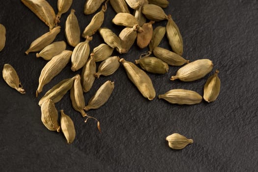 cardamom spice macro detail over black slate stone background