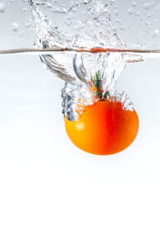 red tomato dropped into water with white background