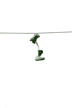 Turnschuhe, welche zusammengebunden über einer Elektroleitung hängen.