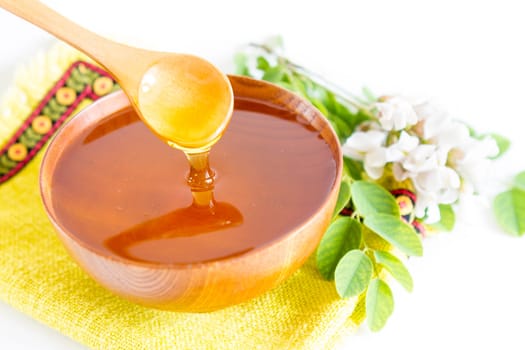 Honey in wooden bowl and acacia plant