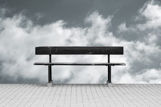 The photograph of a free-standing park bench against a sky background.