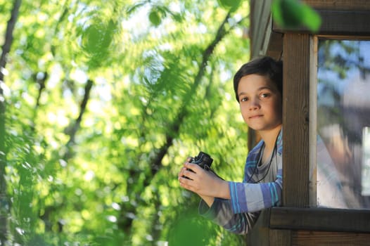 Enfant observant la nature dans sa cabane avec une paire de jumelle