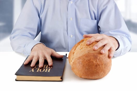 Man holding a Bible  and bread on the table