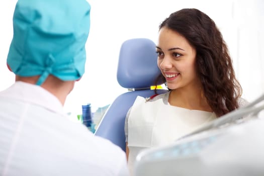 Young woman sitting in a dental chair and looking at doctor