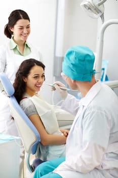 Cheerful patient receiving dental care from a friendly doctor and his assistant