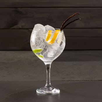 Gin tonic cocktail with ice vanilla lima and lemon on black background