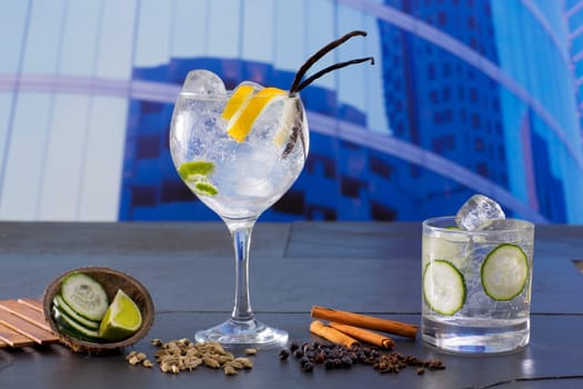 Gin tonic cocktail with spices in urban city buildings background