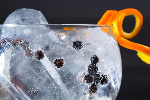 Gin tonic cocktail macro closeup with juniper berries orange