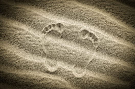 Two footprints in sand on the desert beach, vintage image