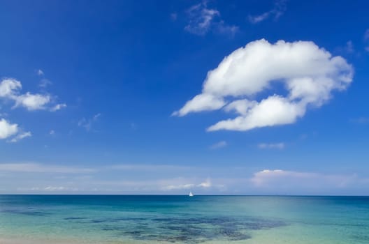 Ocean day landscape with blue cloudy sky and sailboat