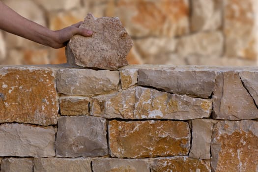 Mason hands working on masonry stone wall stonewall