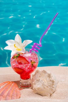 Strawberry cocktail on beach sand with seashell and turquoise beach