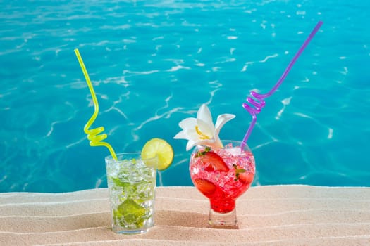 Mojito and strawberry cocktails on white sand beach and turquoise sea