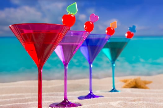 colorful cocktail in a row with cherry on tropical sand beach of turquoise sea