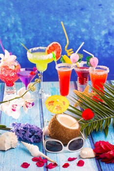 colorful mixed cocktails in tropical blue wood flowers starfish coconut and sunglasses
