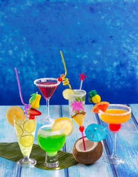 Colorful varied tropical Cocktails in tropical blue wood with coconut mojito pepermint margarita