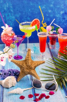 colorful mixed cocktails in tropical blue wood flowers starfish and sunglasses
